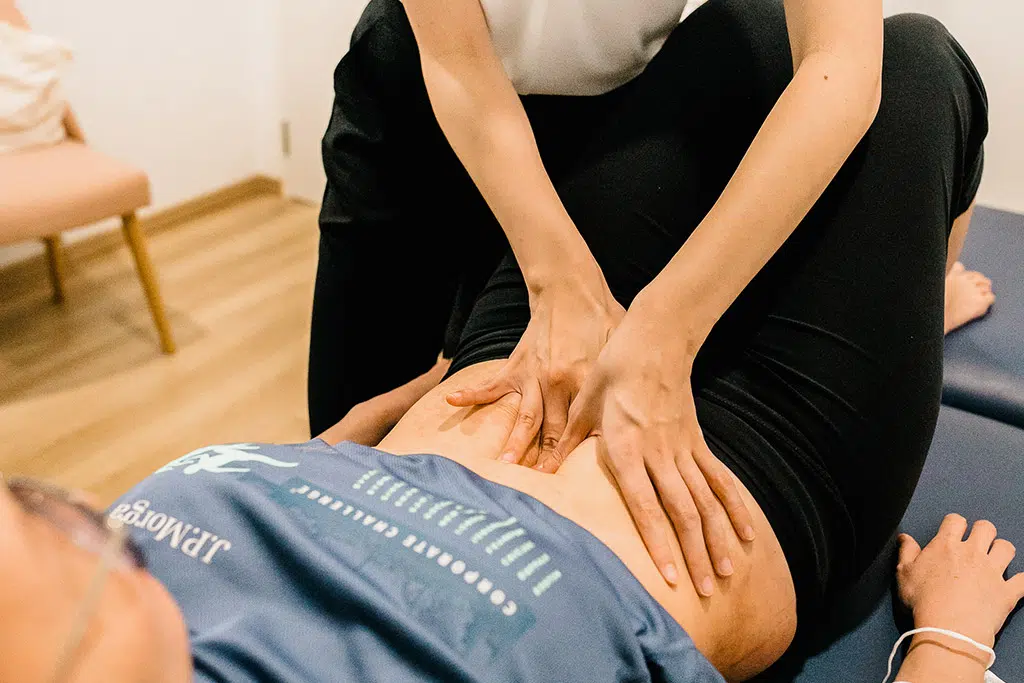 A physiotherapist giving hands on treatment to a client lying on a treatment bed